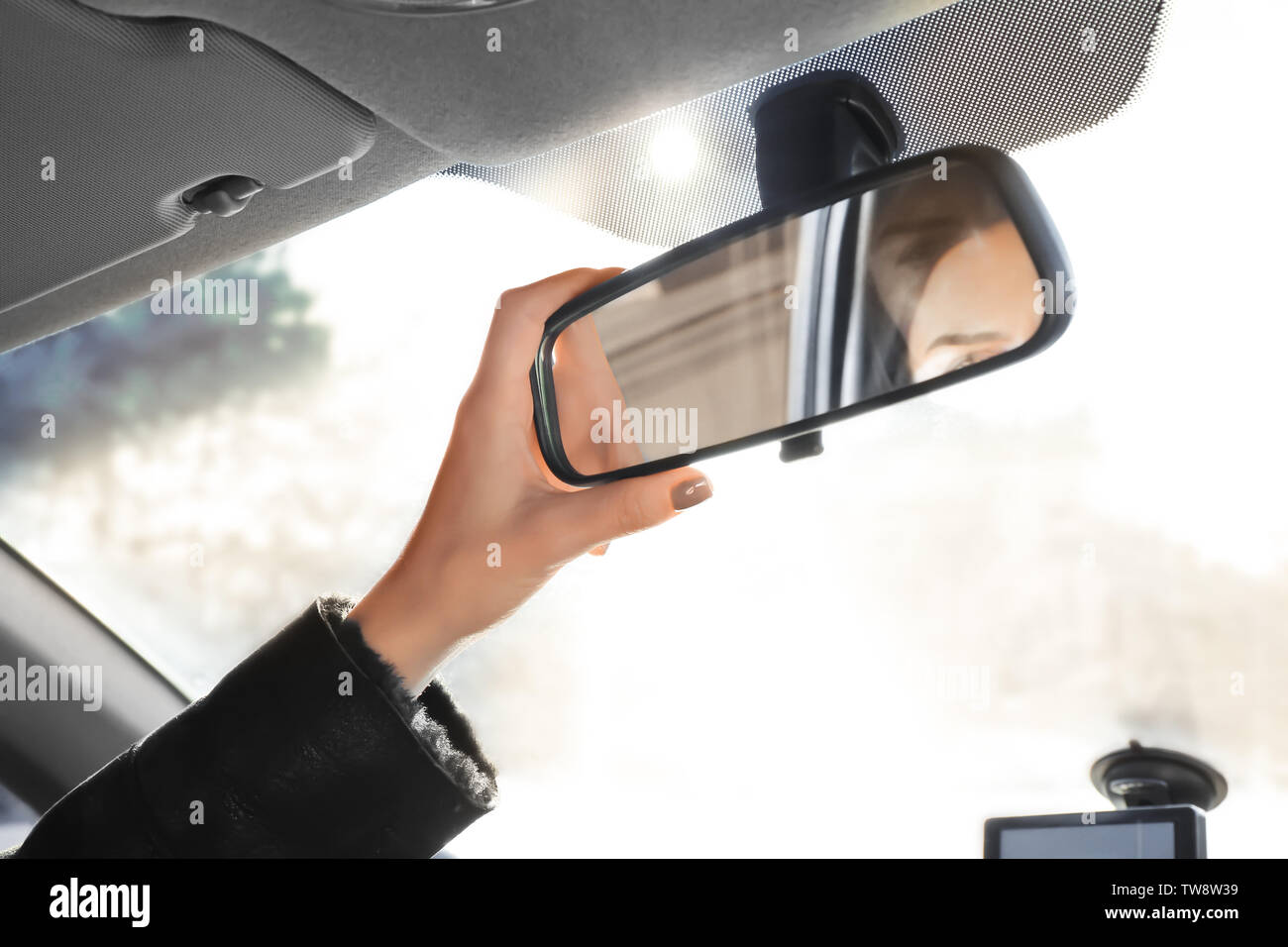 Woman adjusting rear view mirror in car Stock Photo - Alamy