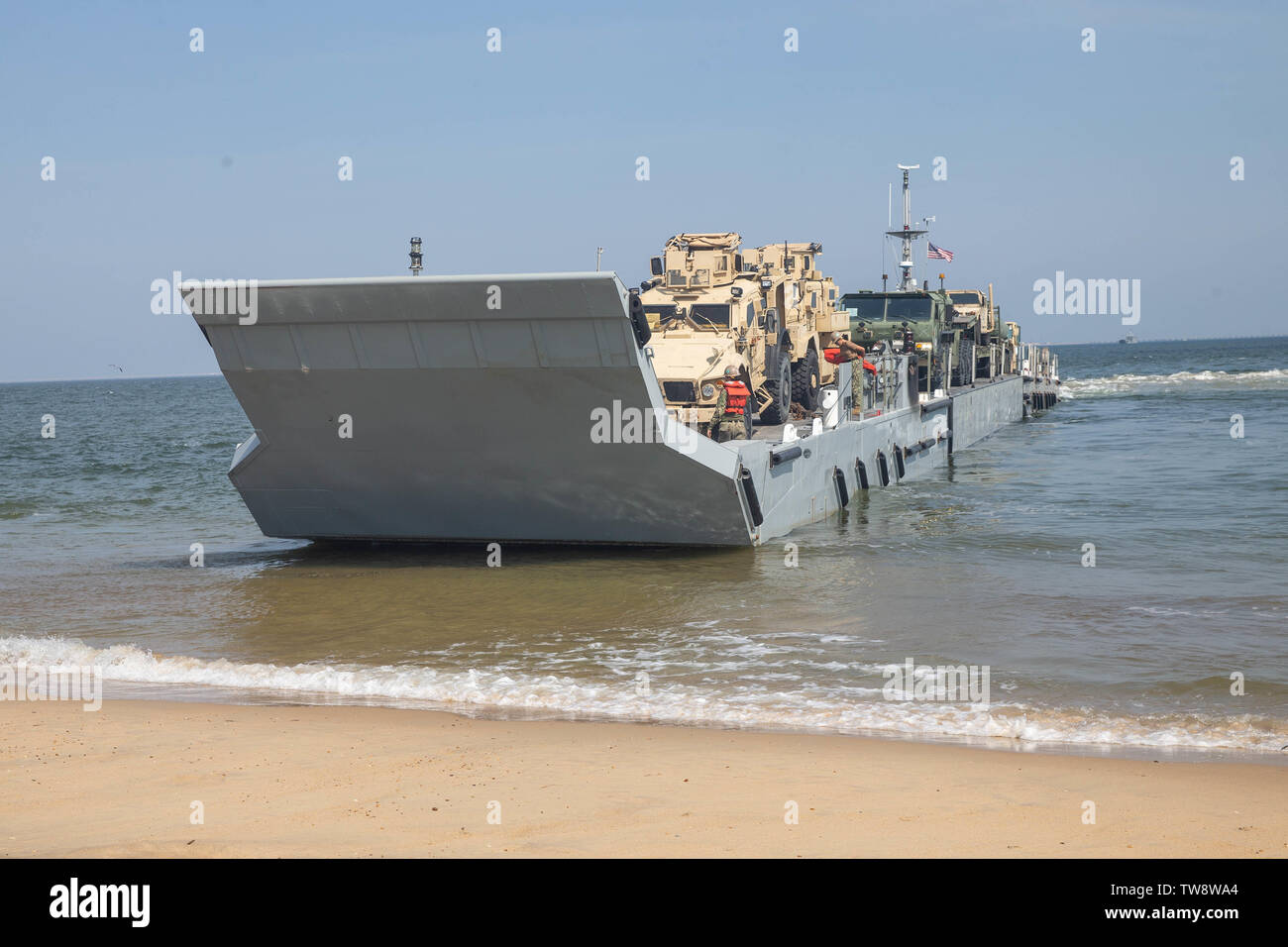 A U.S. Navy improved Navy lighterage system with Amphibious Construction Battalion 2, Naval Beach Group 2, prepares to land on shore with Marine Corps vehicles from 2nd Transportation Support Battalion, Combat Logistics Regiment 2, 2nd Marine Logistics Group during exercise Resolute Sun at Fort Story, Virginia, June 17, 2019. U.S. Marines participated in the exercise to increase combat operational readiness in amphibious and prepositioning operations while conducting joint training with U.S. Army during a joint logistics over the shore scenario. (U.S. Marine Corps photo by Lance Cpl. Scott Jen Stock Photo