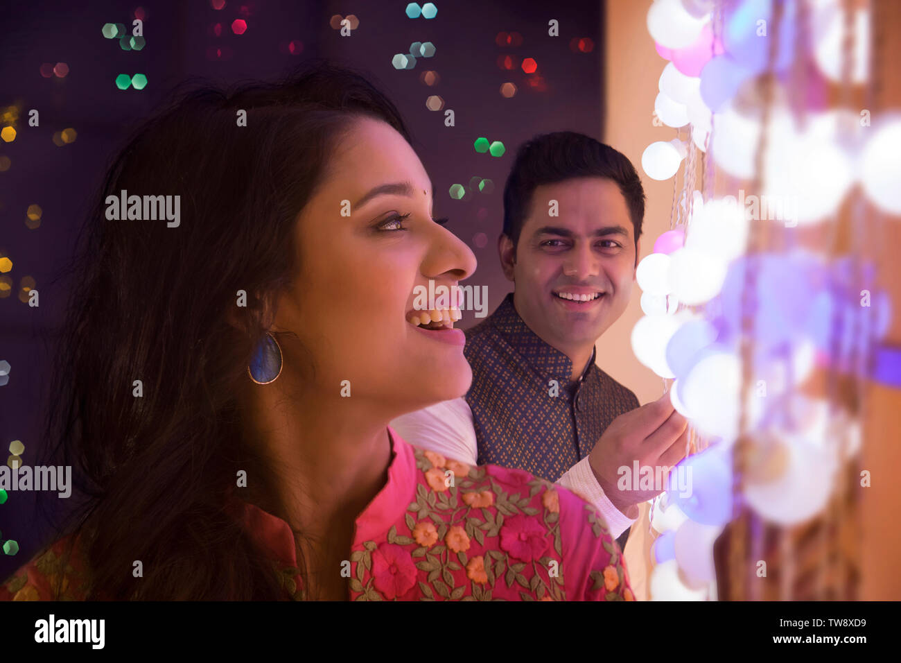 Husband and wife decorating the house with lights on the Stock Photo