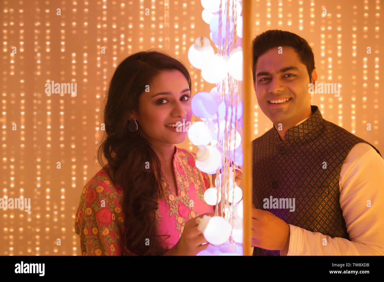 Husband and wife posing standing next to Diwali lights Stock Photo Alamy