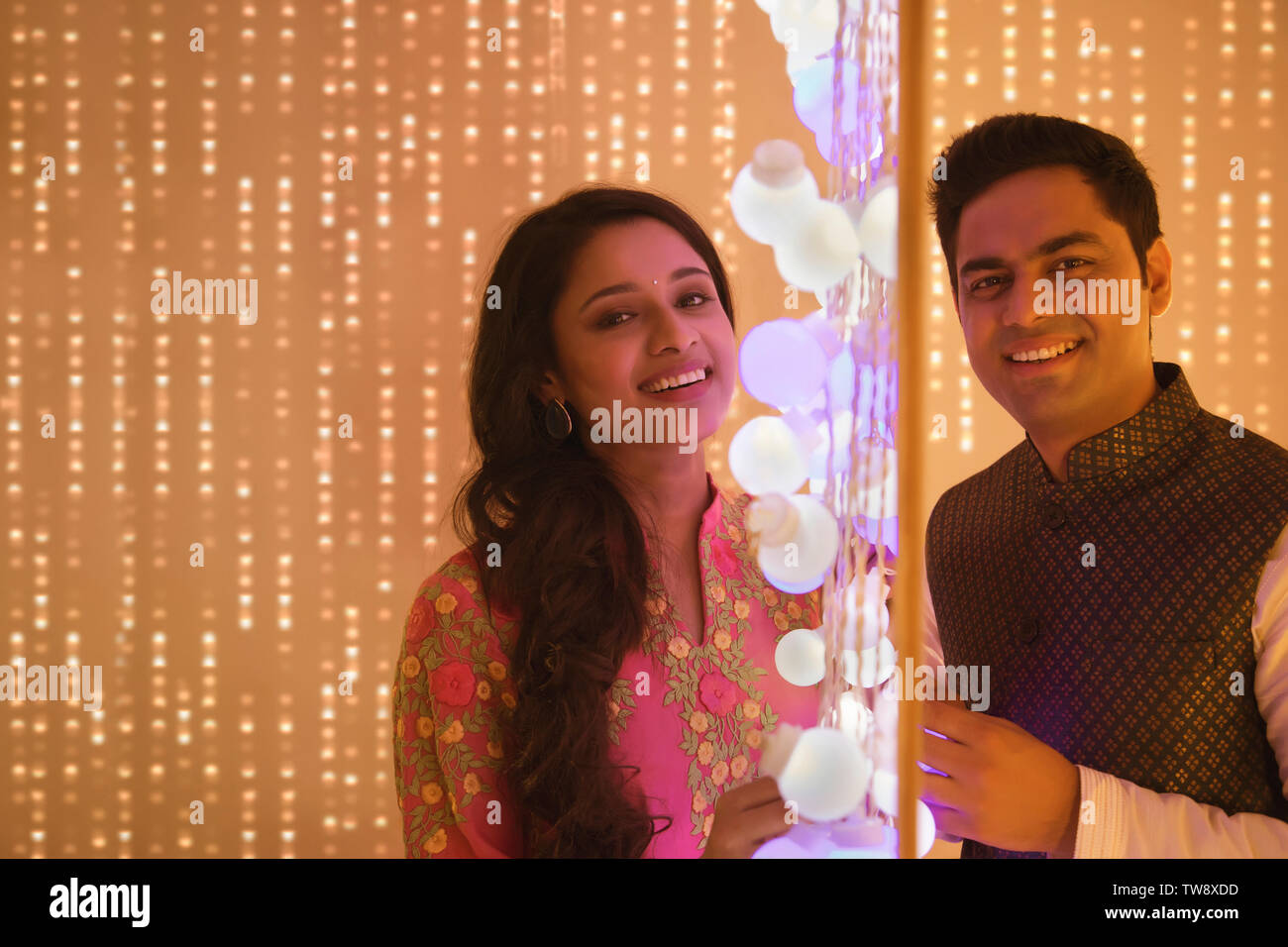 Husband and wife posing standing next to Diwali lights Stock Photo Alamy