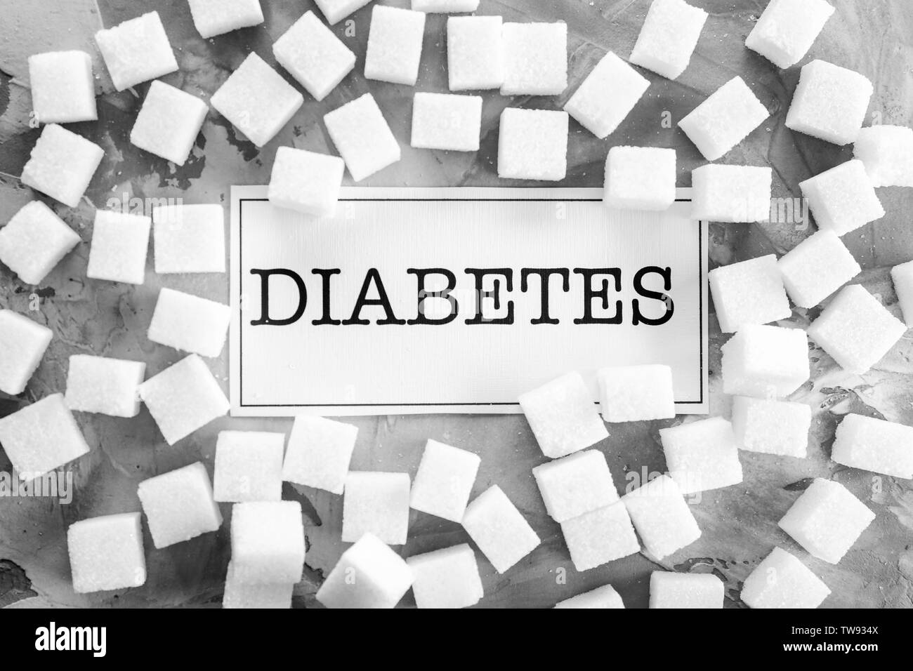 Card with word 'Diabetes' and sugar cubes on grey background Stock Photo