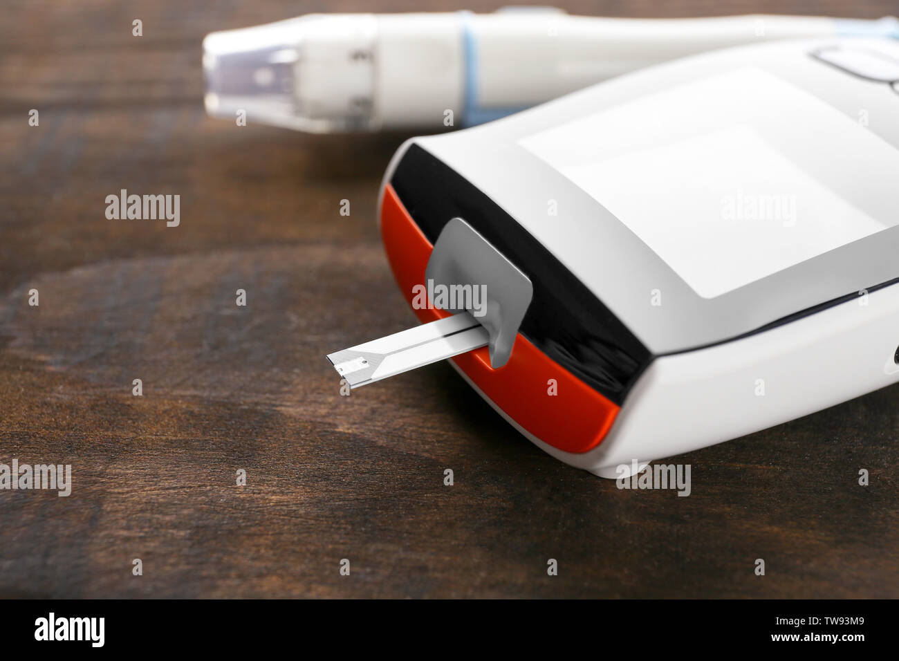 Digital glucometer on wooden background, closeup. Diabetes management