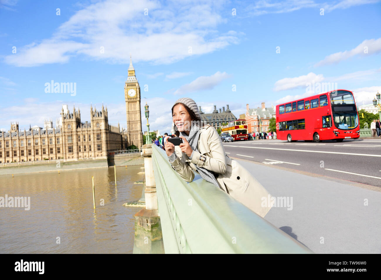 London travel woman tourist by Big Ben and red double decker bus. Girl taking photo on Westminster Bridge with smart phone camera over River Thames, London, England, Great Britain, UK. Stock Photo