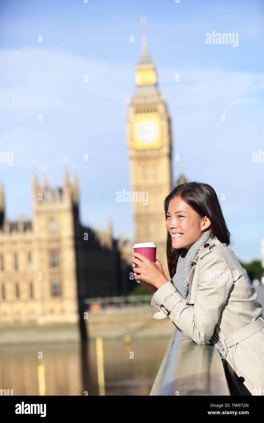 London woman drinking coffee happy by Big Ben laughing. Young female professional on Westminster Bridge, London, England. Beautiful young multiracial Asian Caucasian girl. Stock Photo