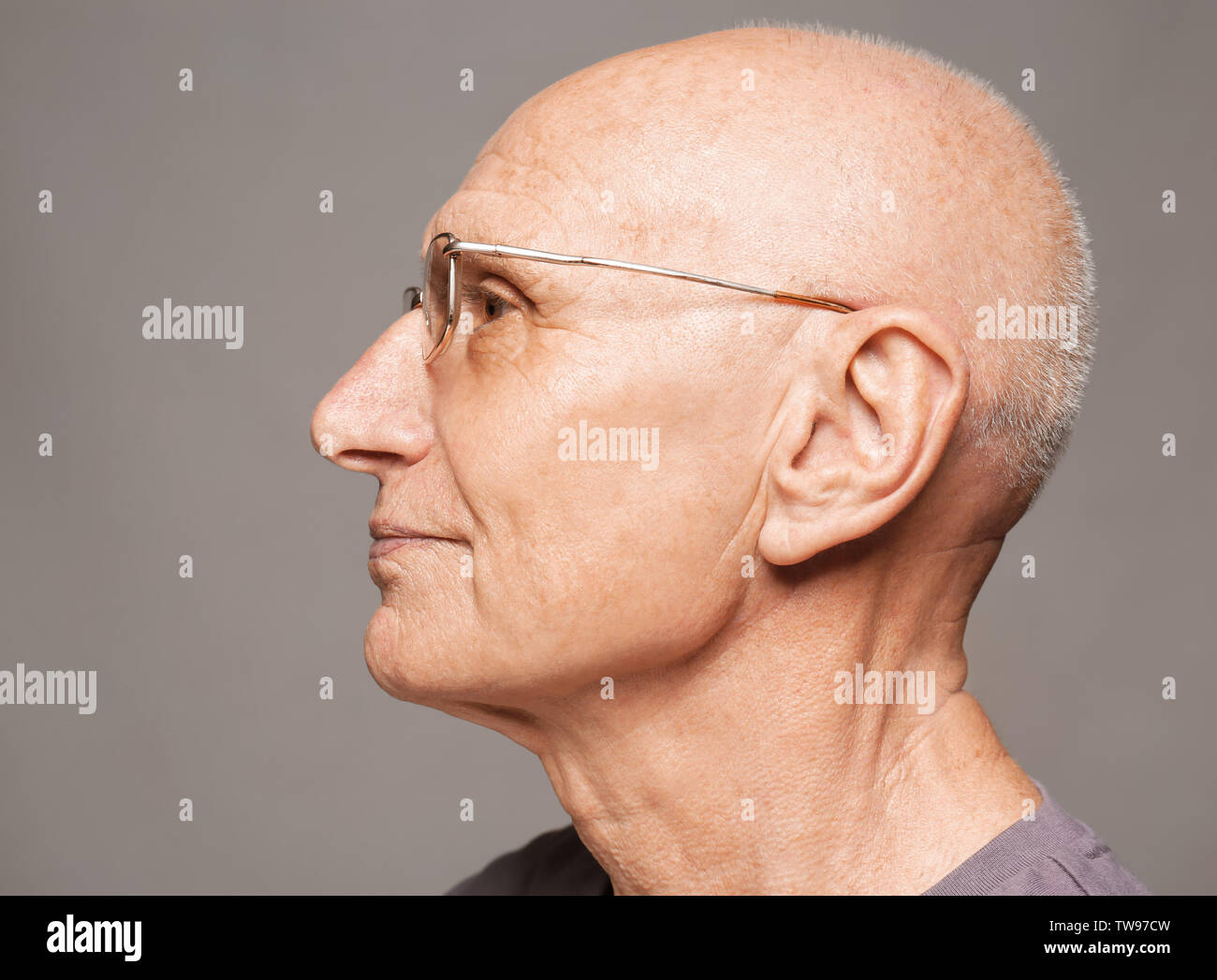 Elderly man on grey background. Hearing problem Stock Photo