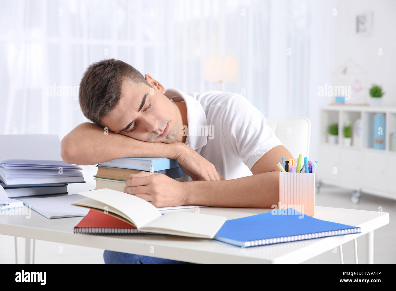 Tired Student Sleeping On Stack Of Books At His Desk Preparing