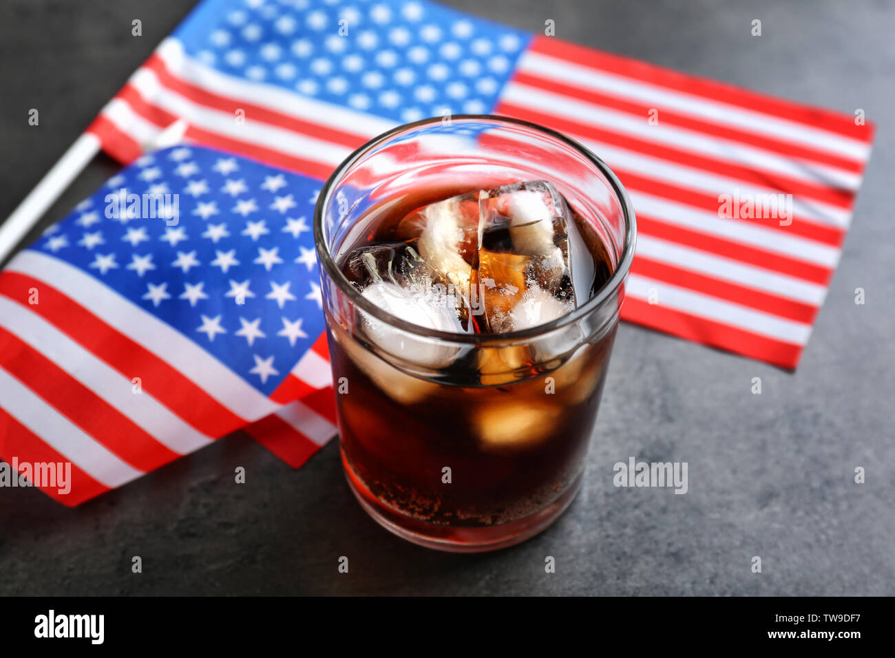 Glass of cold cola with flag of the USA on grey background Stock Photo