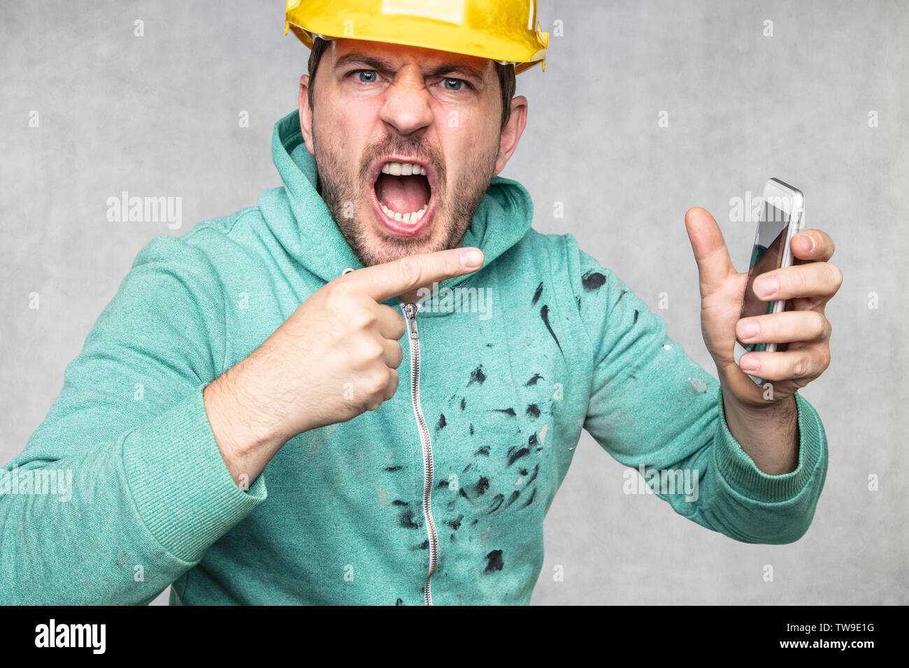 construction supervisor is shouting to a cell phone, pointing with his finger Stock Photo