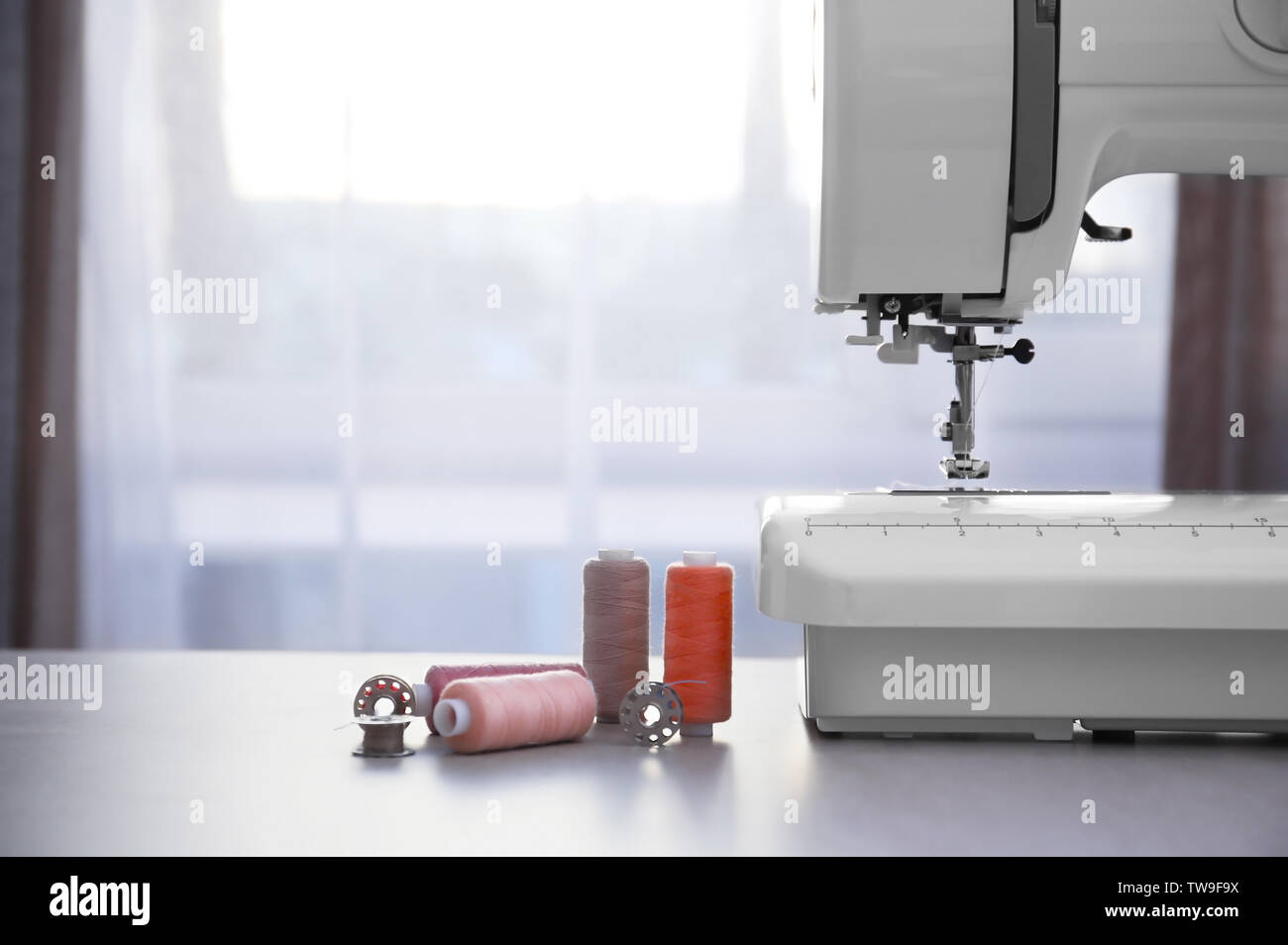 Modern sewing machine with threads on table Stock Photo - Alamy