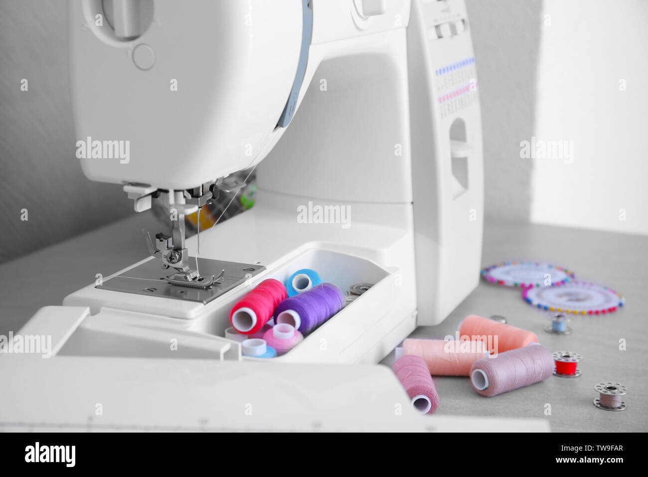 Modern sewing machine with threads on table Stock Photo - Alamy