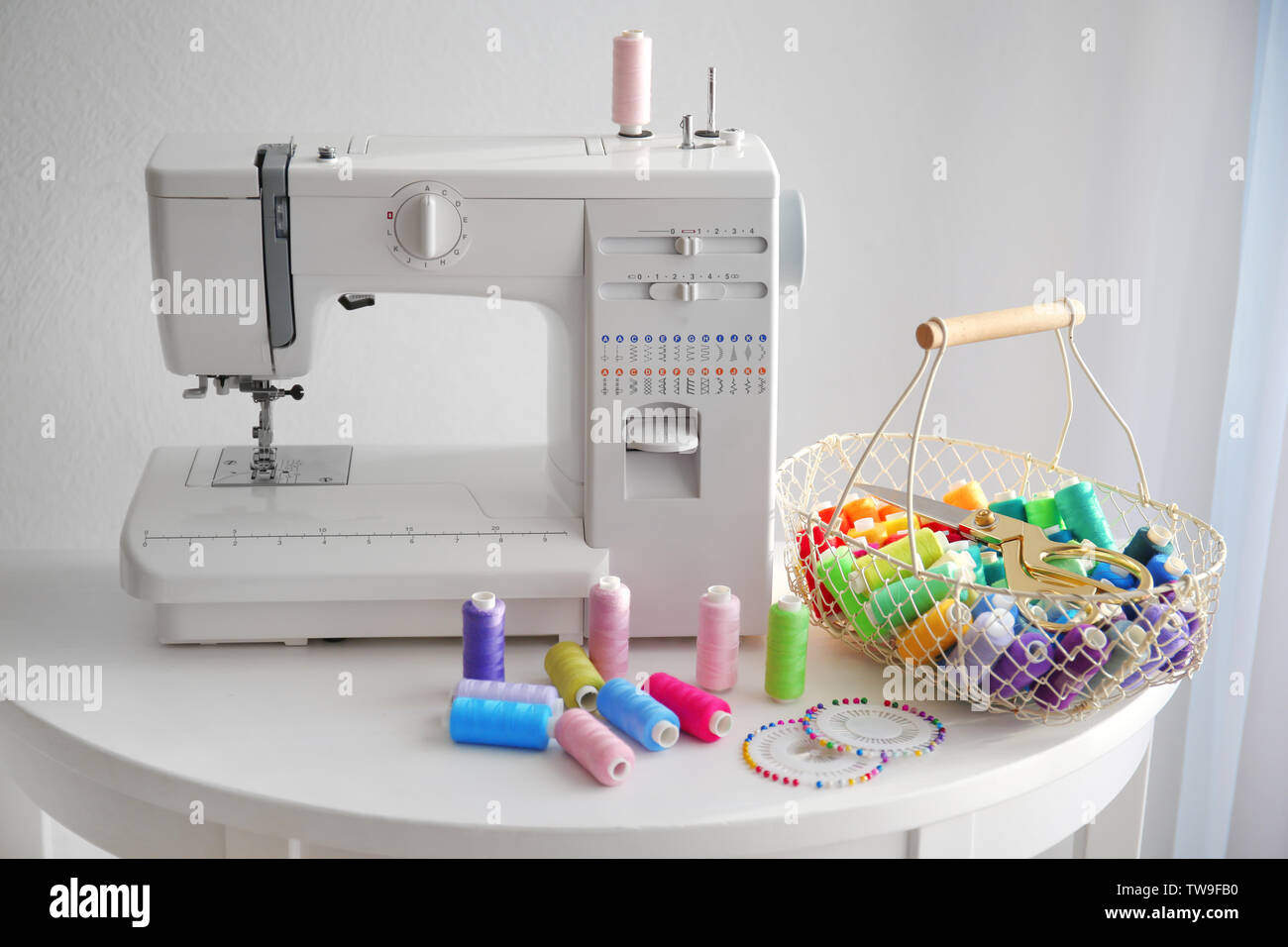 Modern sewing machine with threads on table Stock Photo - Alamy