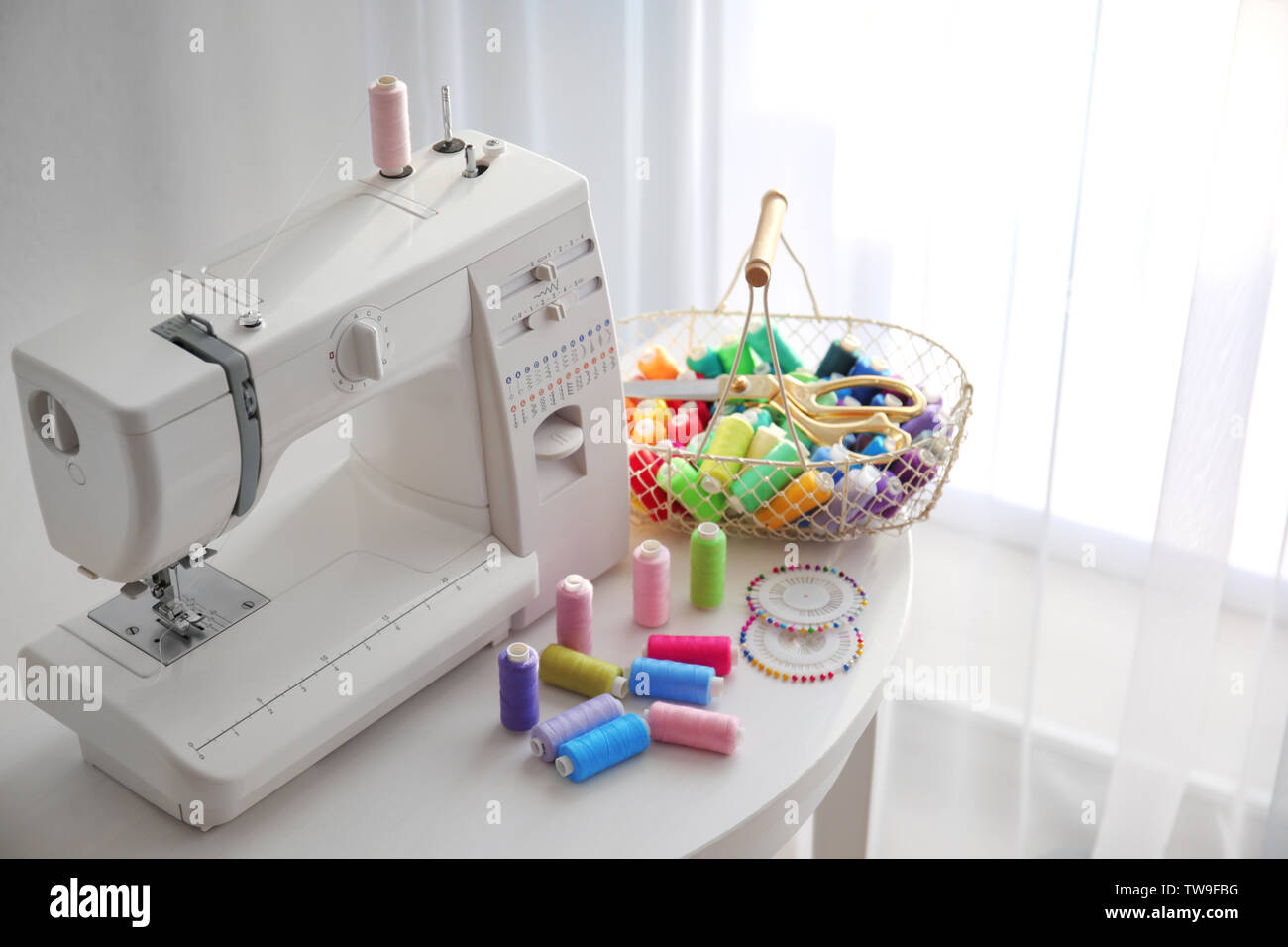 Modern sewing machine with threads on table Stock Photo - Alamy
