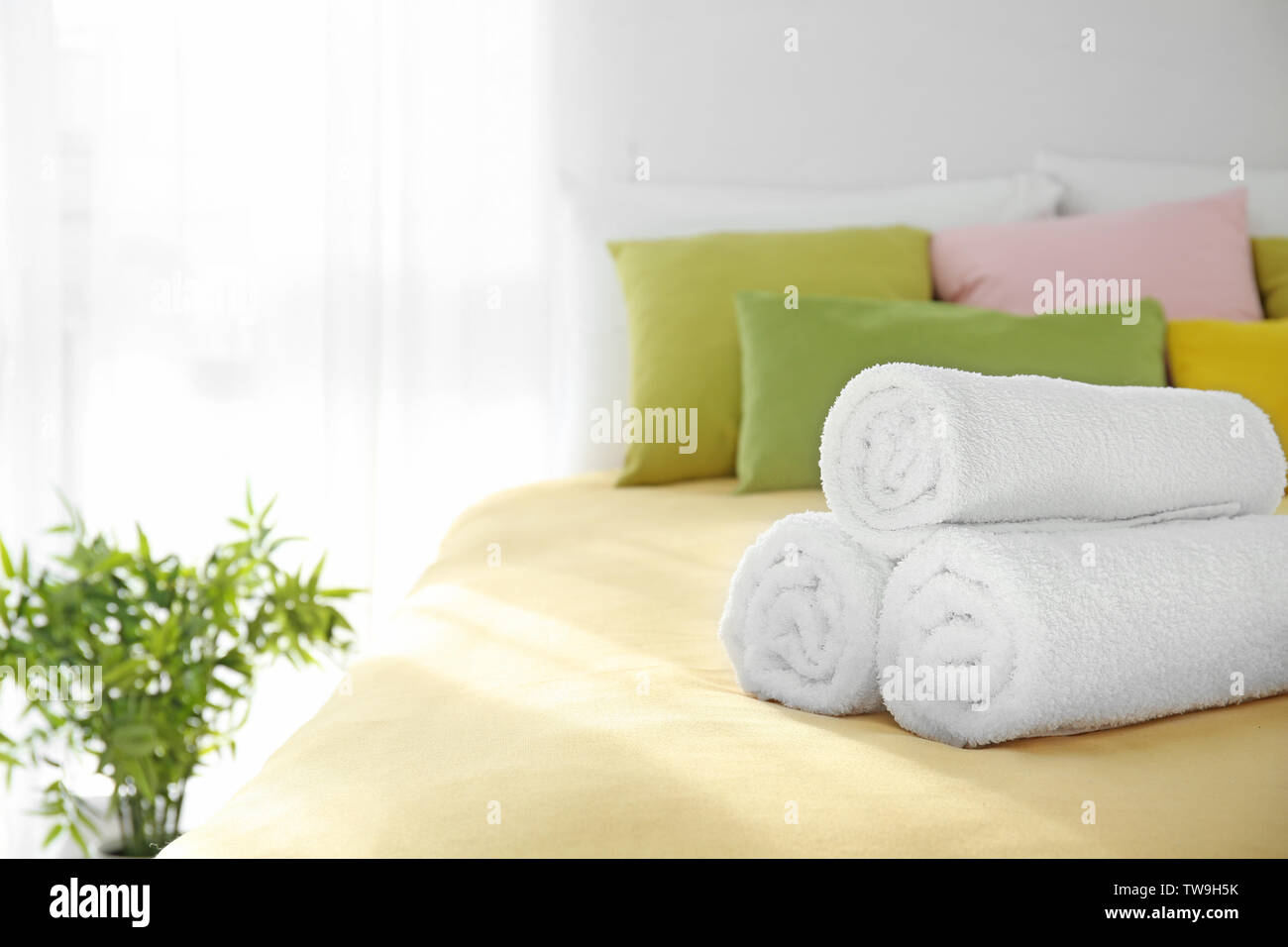 Rolled white towels on bed Stock Photo