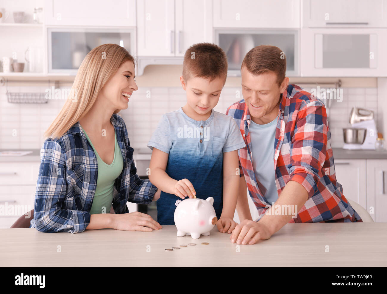 Happy family putting coin into piggy bank at home Stock Photo - Alamy