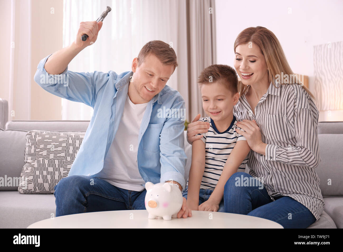 Happy family breaking piggy bank with hammer at home Stock Photo - Alamy