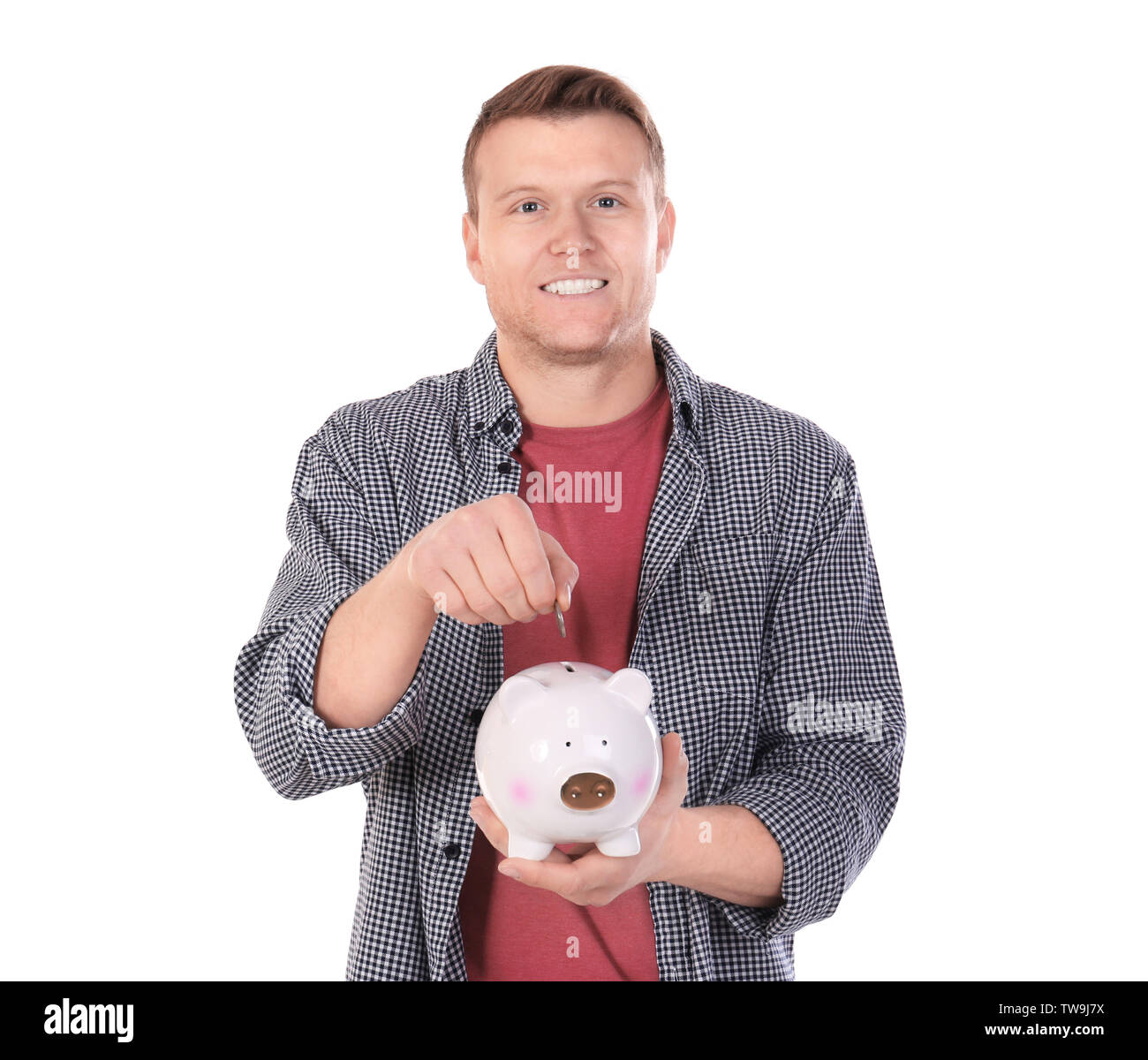 Young man putting coin into piggy bank on white background Stock Photo ...
