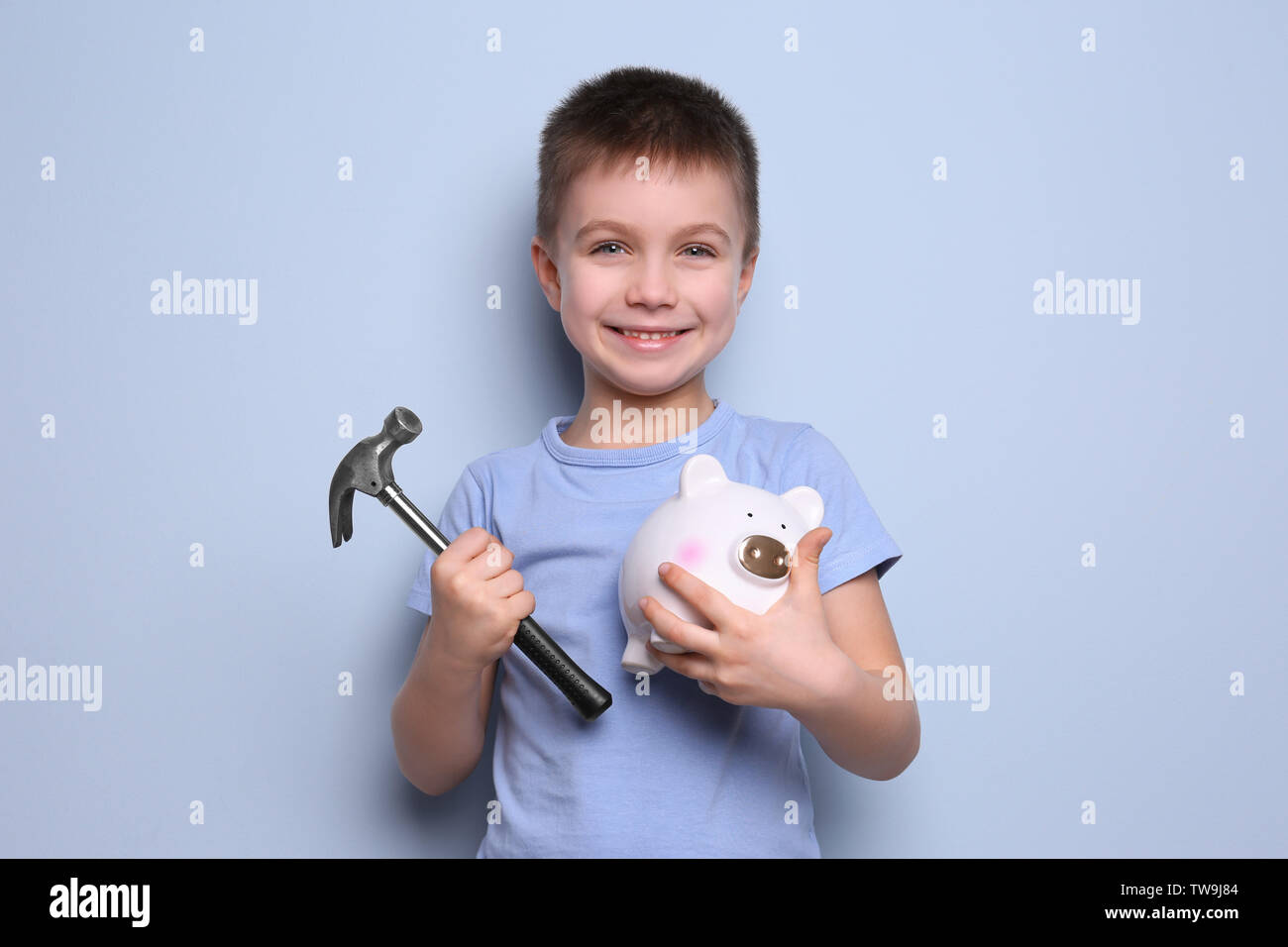 Cute boy holding hammer and piggy bank on color background Stock Photo ...