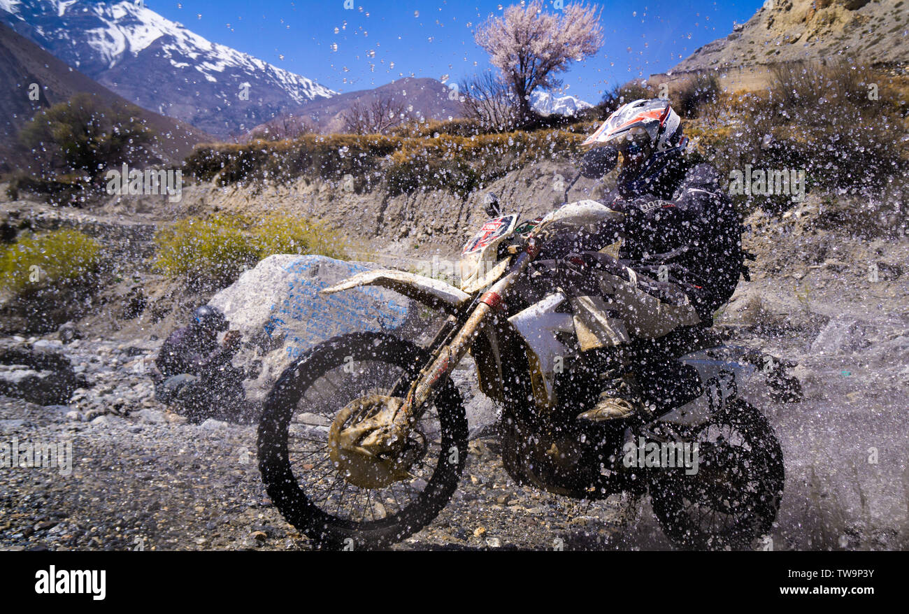Motorcycle touring in the Mustang, Nepal.  Picture shows a rider crossing a river near Kagbeni, Upper Mustang Stock Photo
