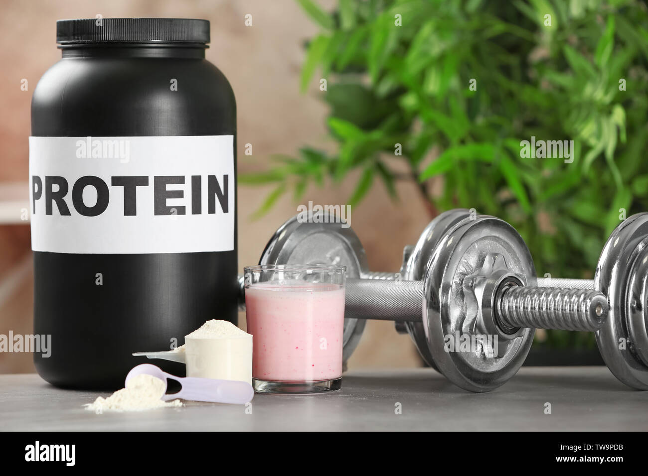 Protein Powder In Scoope With Dumbbells In Background - Whey Stock