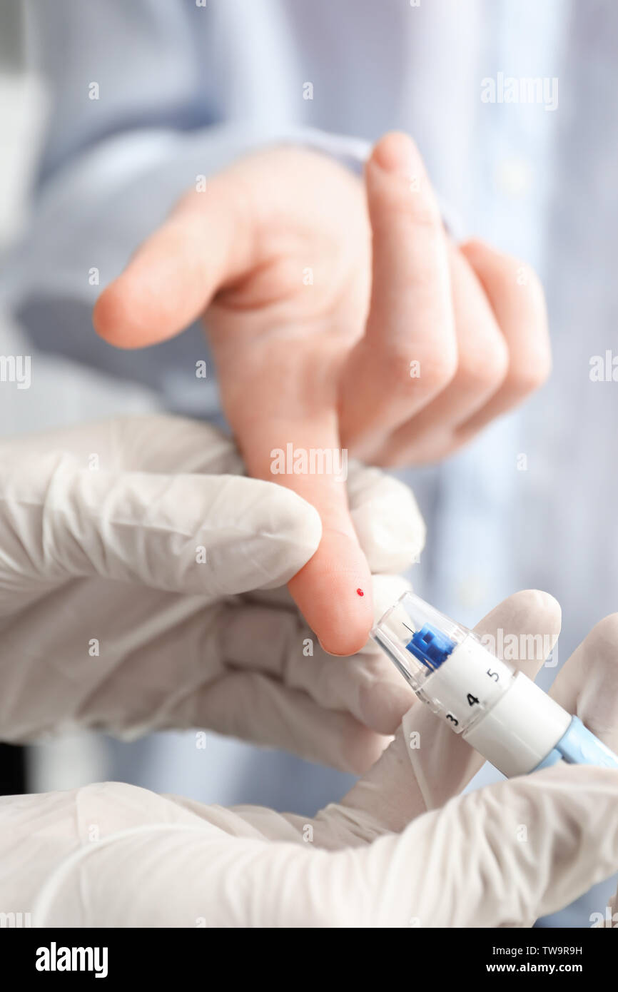 Doctor taking patient's blood sample with lancet pen, closeup. Diabetes