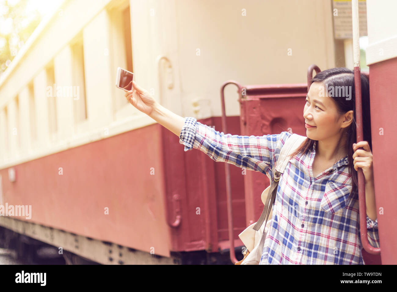 happy young Asian traveller woman taking selfie photo from mobile phone at train station while traveling Stock Photo