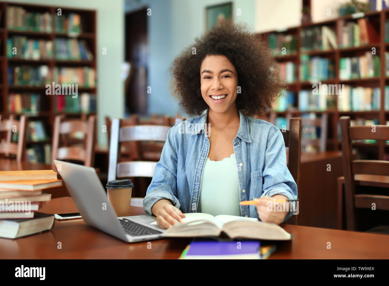 African American student with laptop studying in library Stock Photo ...