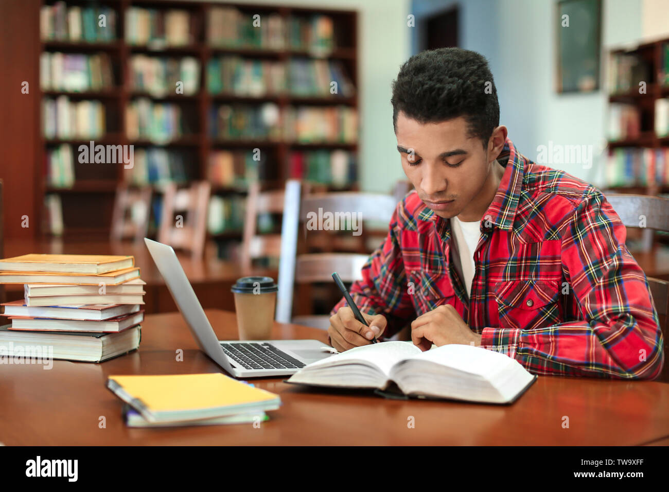 African American student with laptop studying in library Stock Photo ...