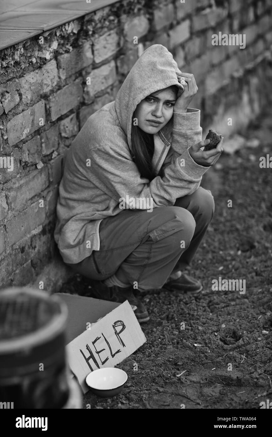 Helping Poor Homeless poor woman sitting outdoors near piece of cardboard with word ...