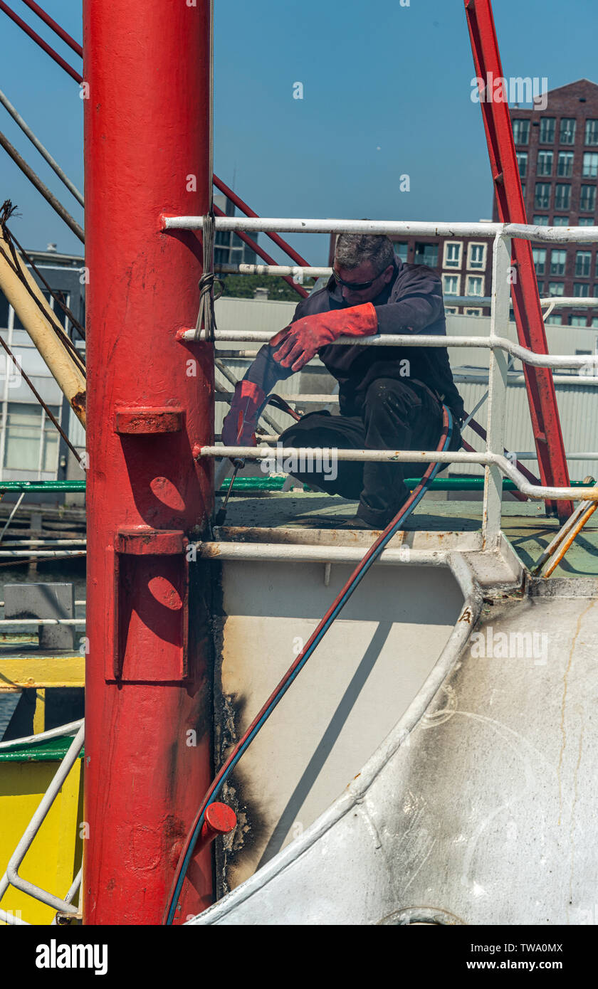 steel worker is working with a cutting torch on the deck of a ship Stock Photo