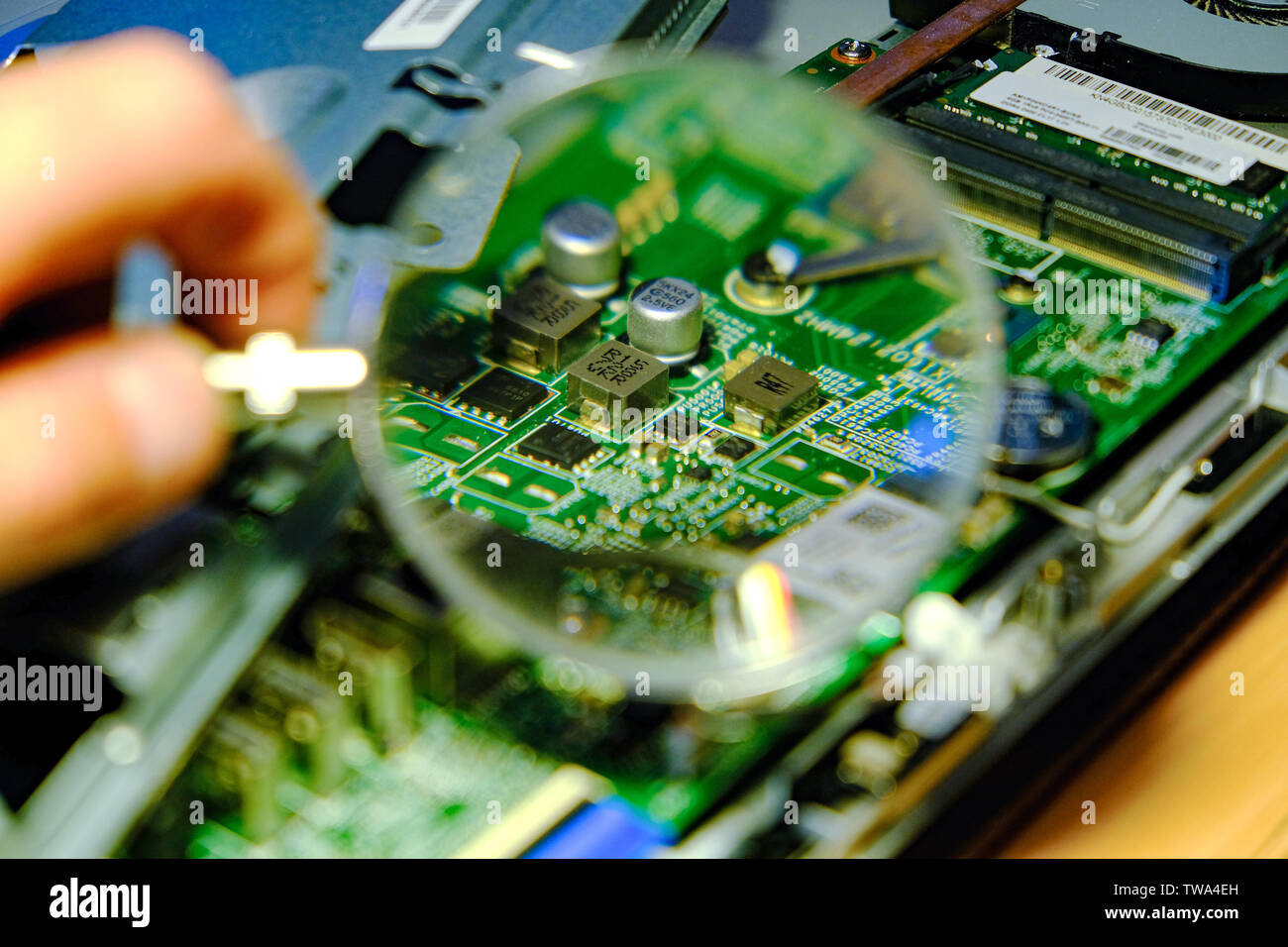 The motherboard is magnified through a magnifying glass. Hardware upgrades computer processor of the service component of the motherboard. The concept Stock Photo
