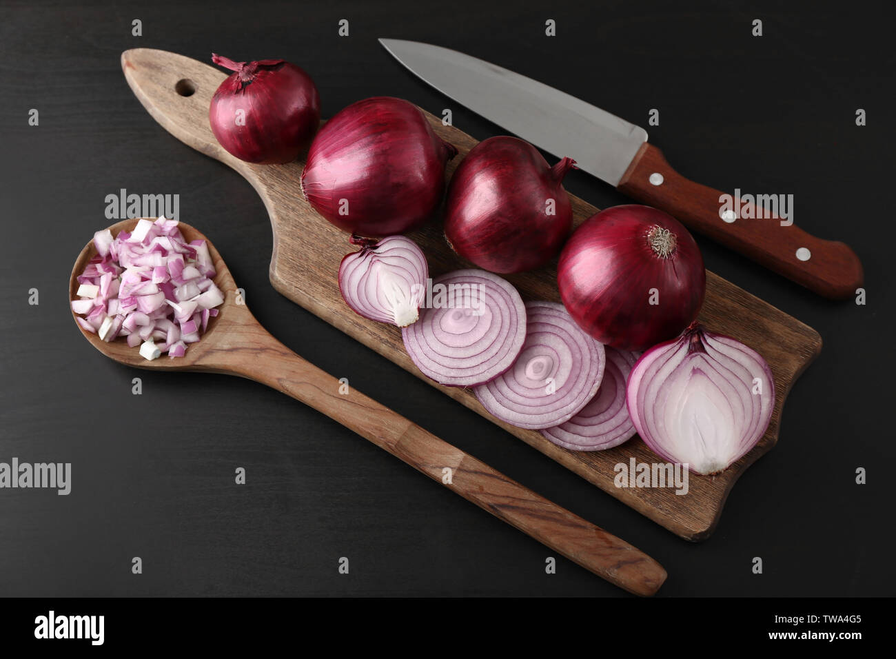 Wooden board with cut and whole red onions on black background Stock ...
