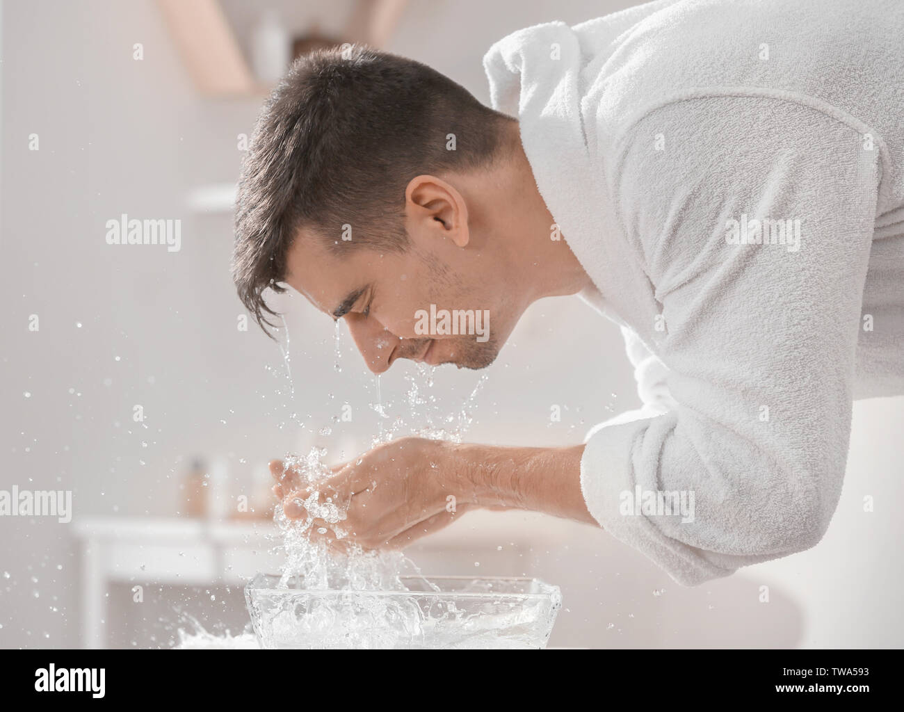Man spraying water on his face after shaving in bathroom Stock Photo