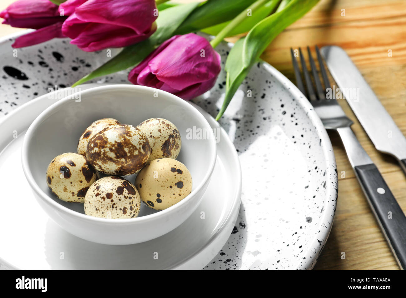 Beautiful festive Easter table setting with quail eggs and tulips, closeup Stock Photo
