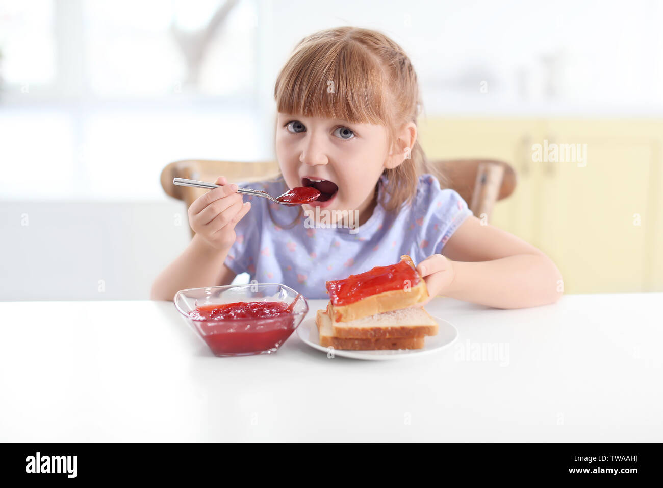 Cute little girl eating jam at home Stock Photo Alamy