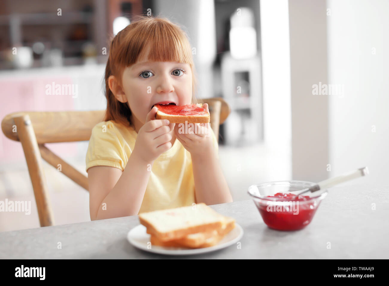 Cute little girl eating toast with jam at home Stock Photo Alamy