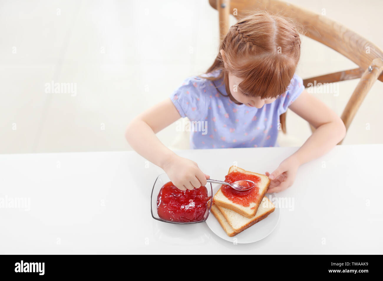 Cute little girl spreading jam on toast at home Stock Photo Alamy