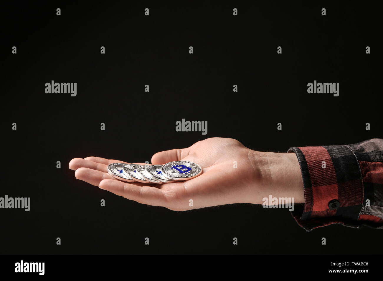 Man holding silver bitcoin on black background Stock Photo