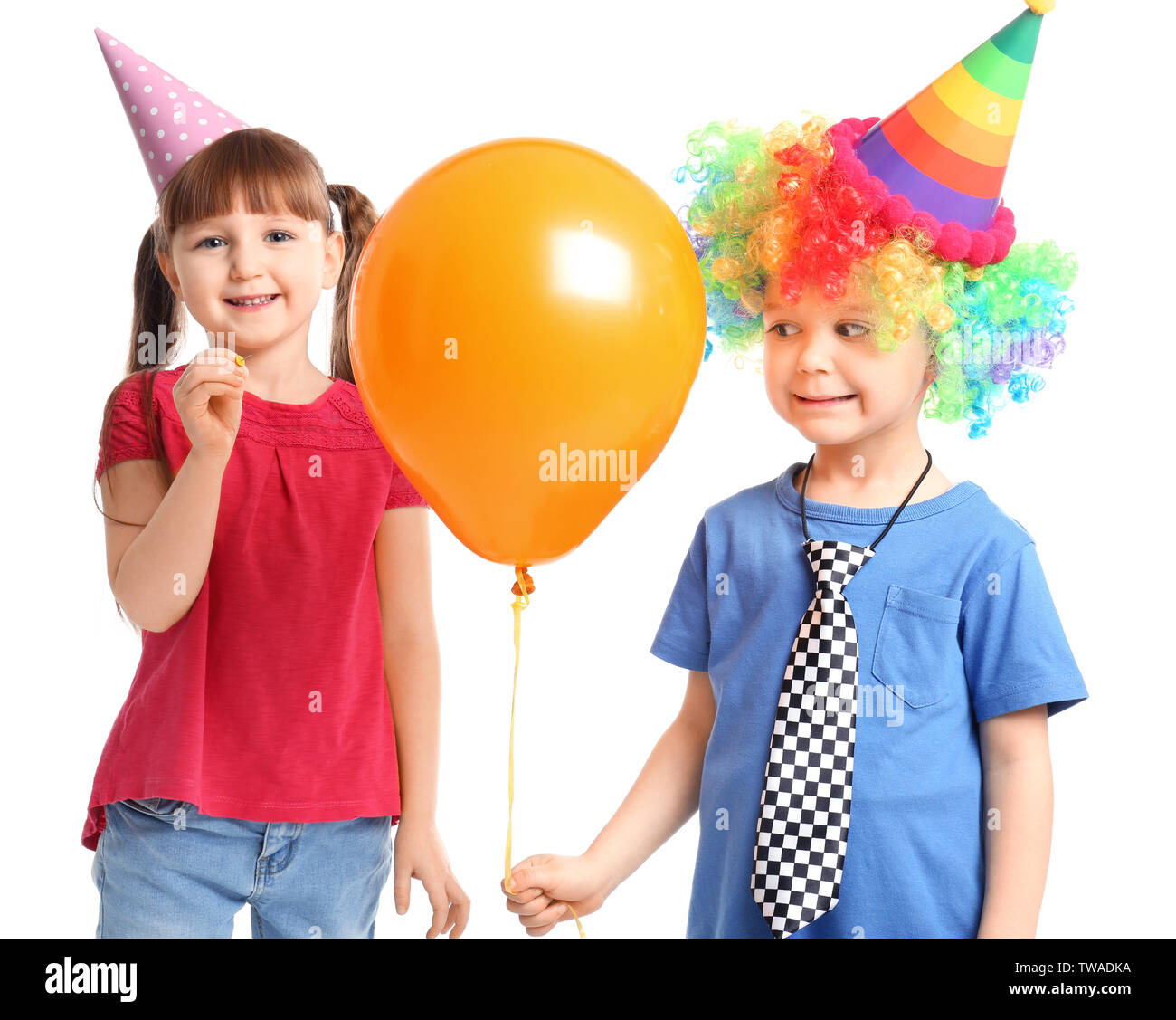 Cute little girl popping brother's balloon with pin on white background. April fool's day celebration Stock Photo