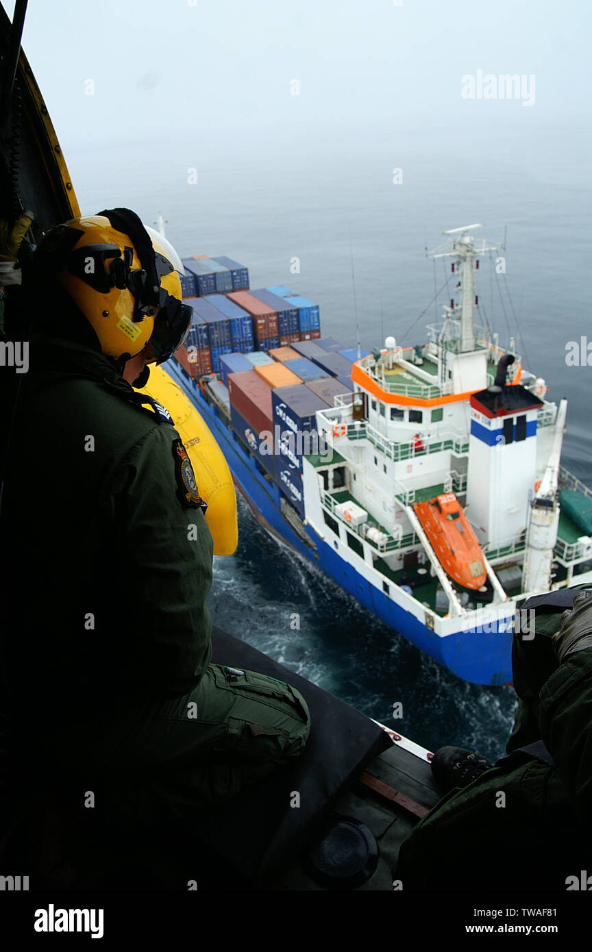 Rescue helicopter approaching container ship Stock Photo