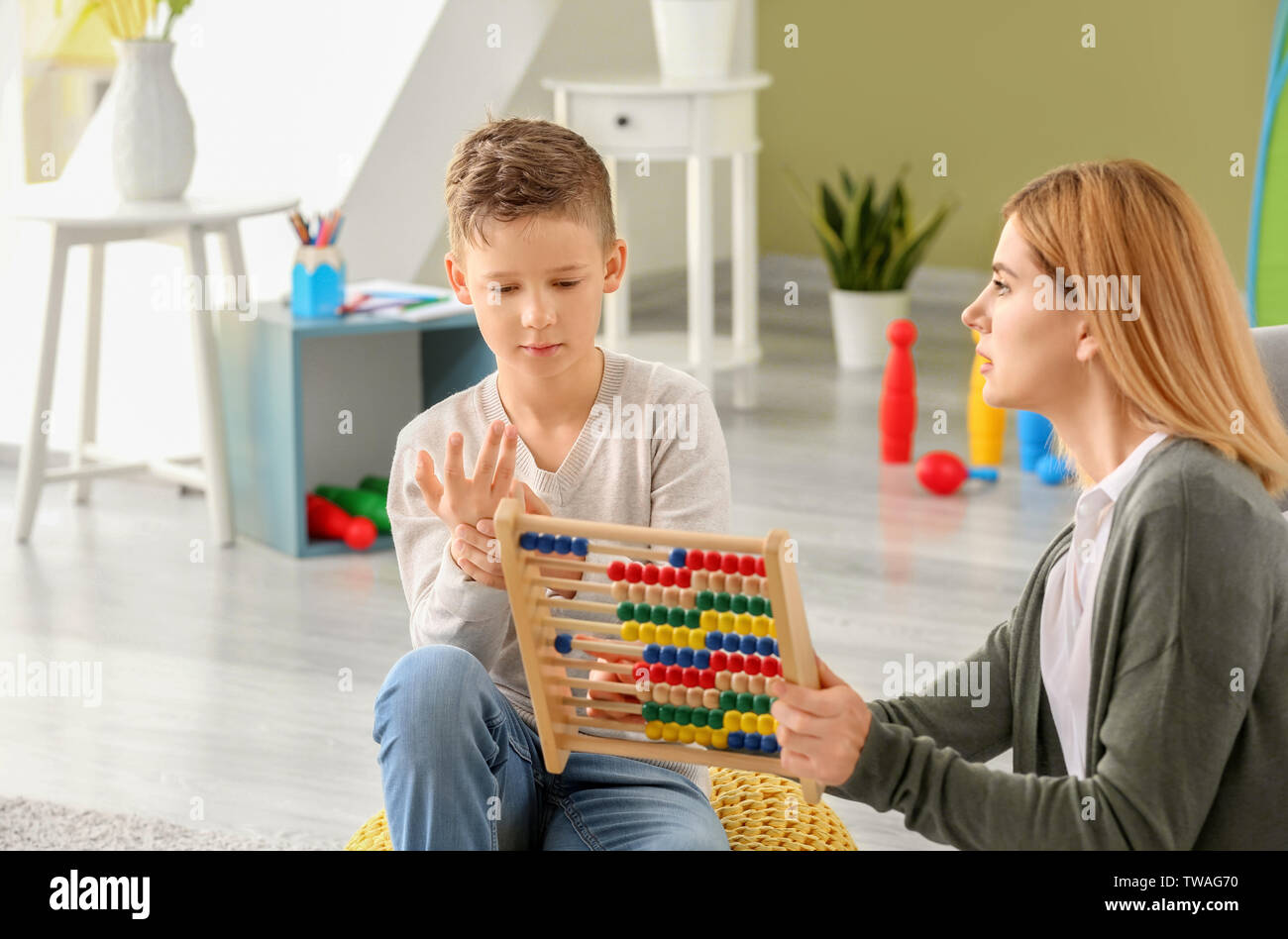 Female psychologist working with boy suffering from autistic disorder