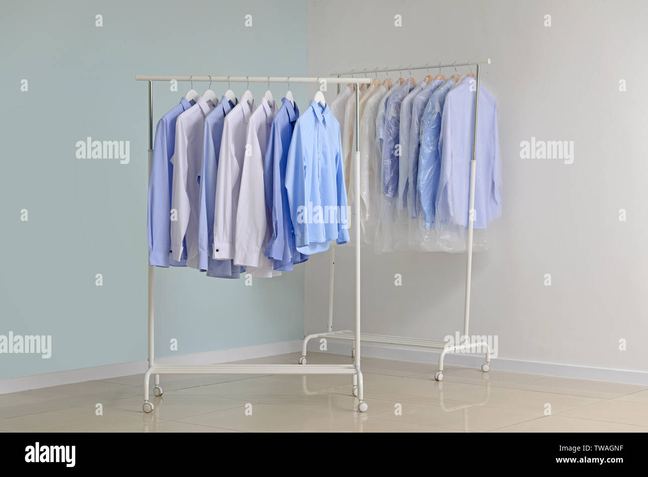 Racks with clothes after dry-cleaning near light wall Stock Photo - Alamy