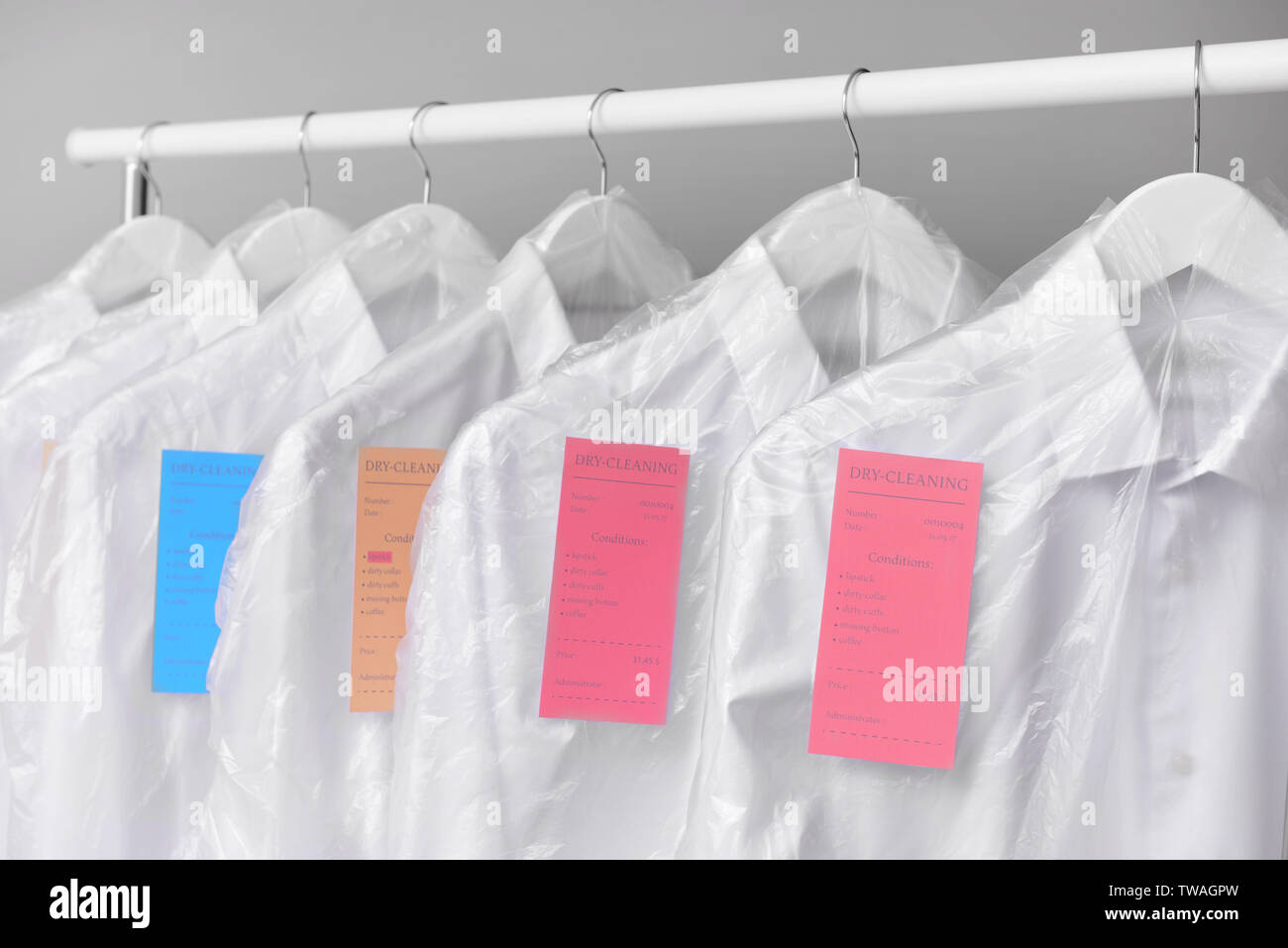 Rack with clothes after dry-cleaning on light background Stock Photo