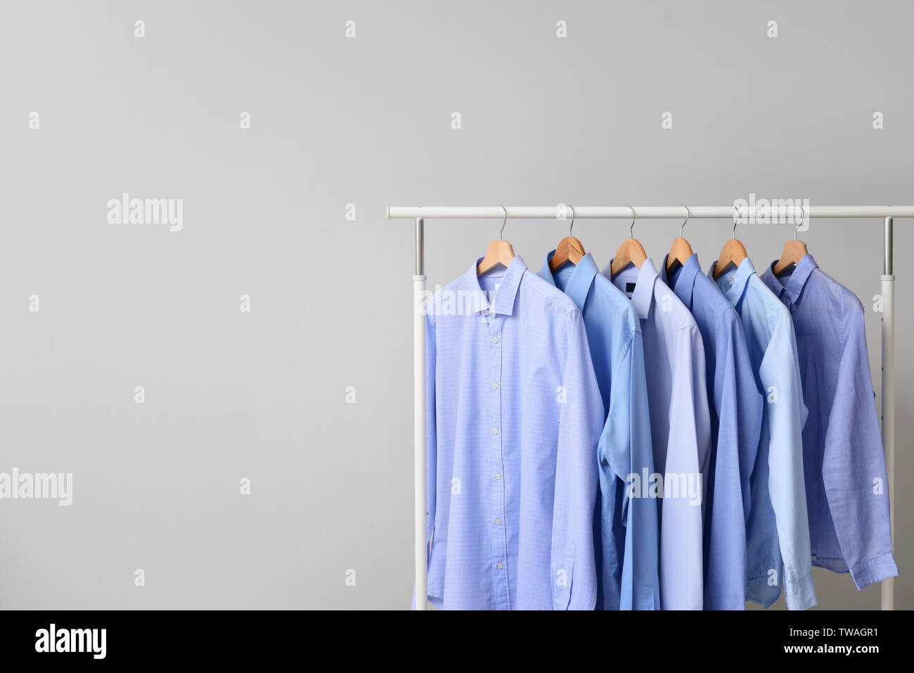 Rack with clothes after dry-cleaning on light background Stock Photo