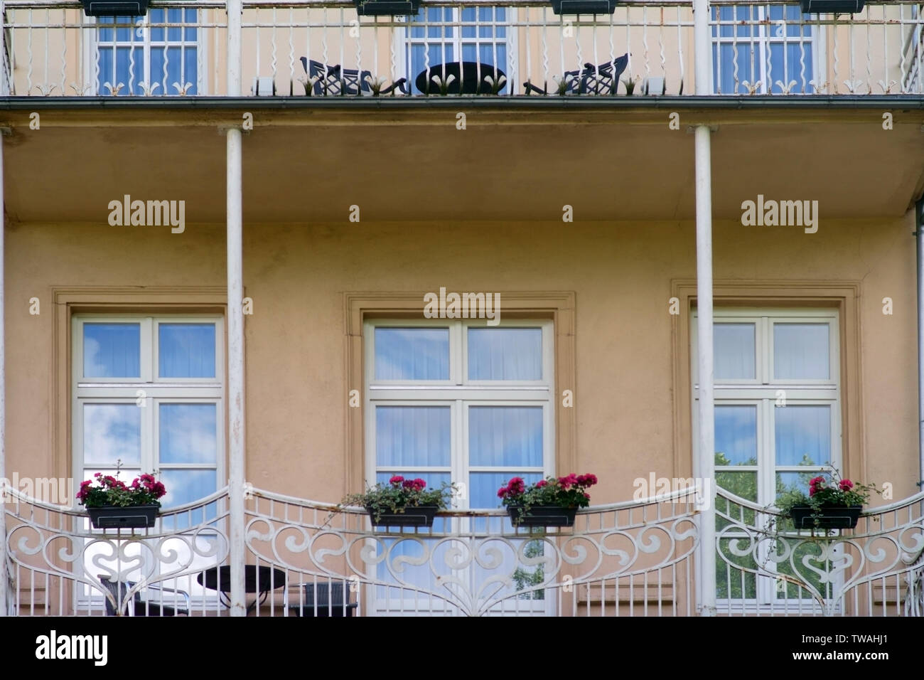 The facade of a villa with a terrace or a Venetian-style balcony with balcony flowers. Stock Photo