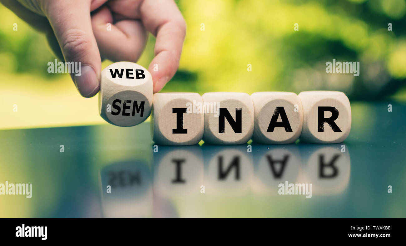 Modern Webinar or traditional Seminar? Hand turns a cube and changes the word "seminar" to "webinar". Stock Photo