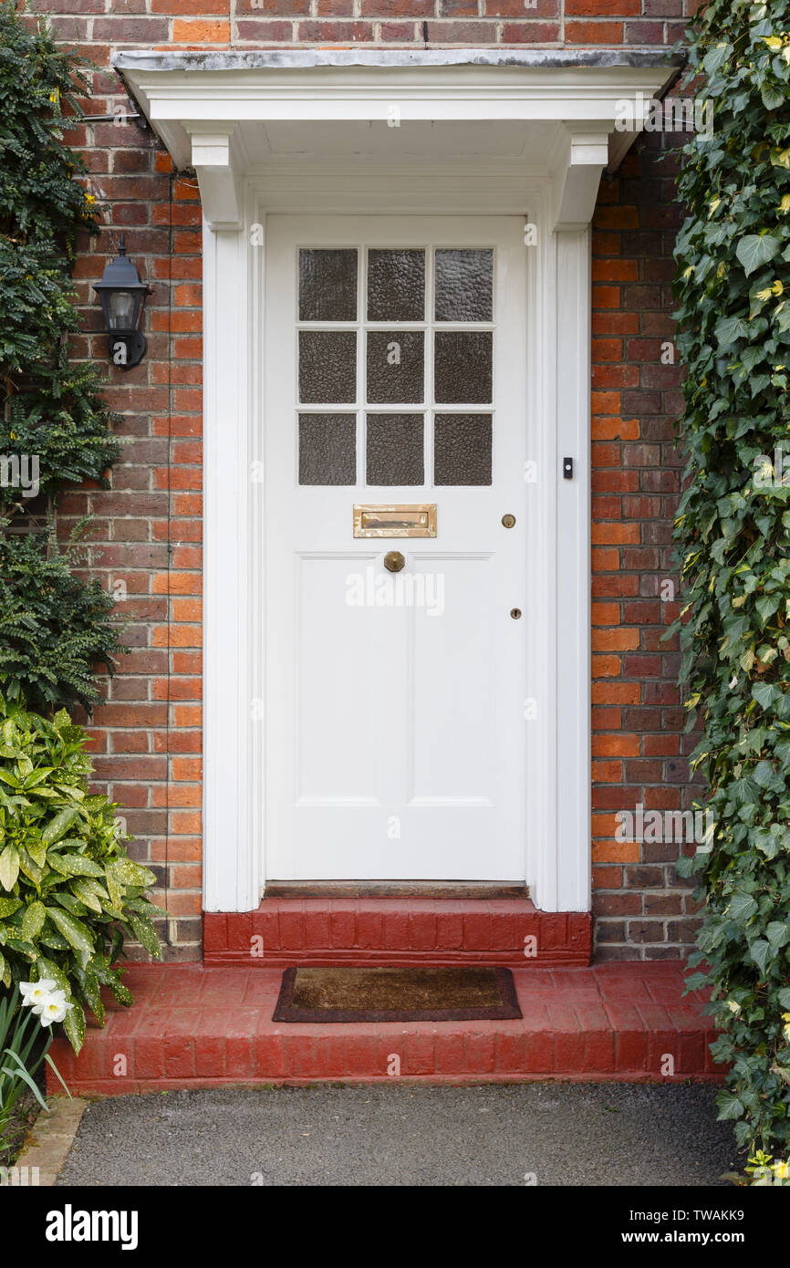 Front door of a period English house with white wooden half glazed door Stock Photo