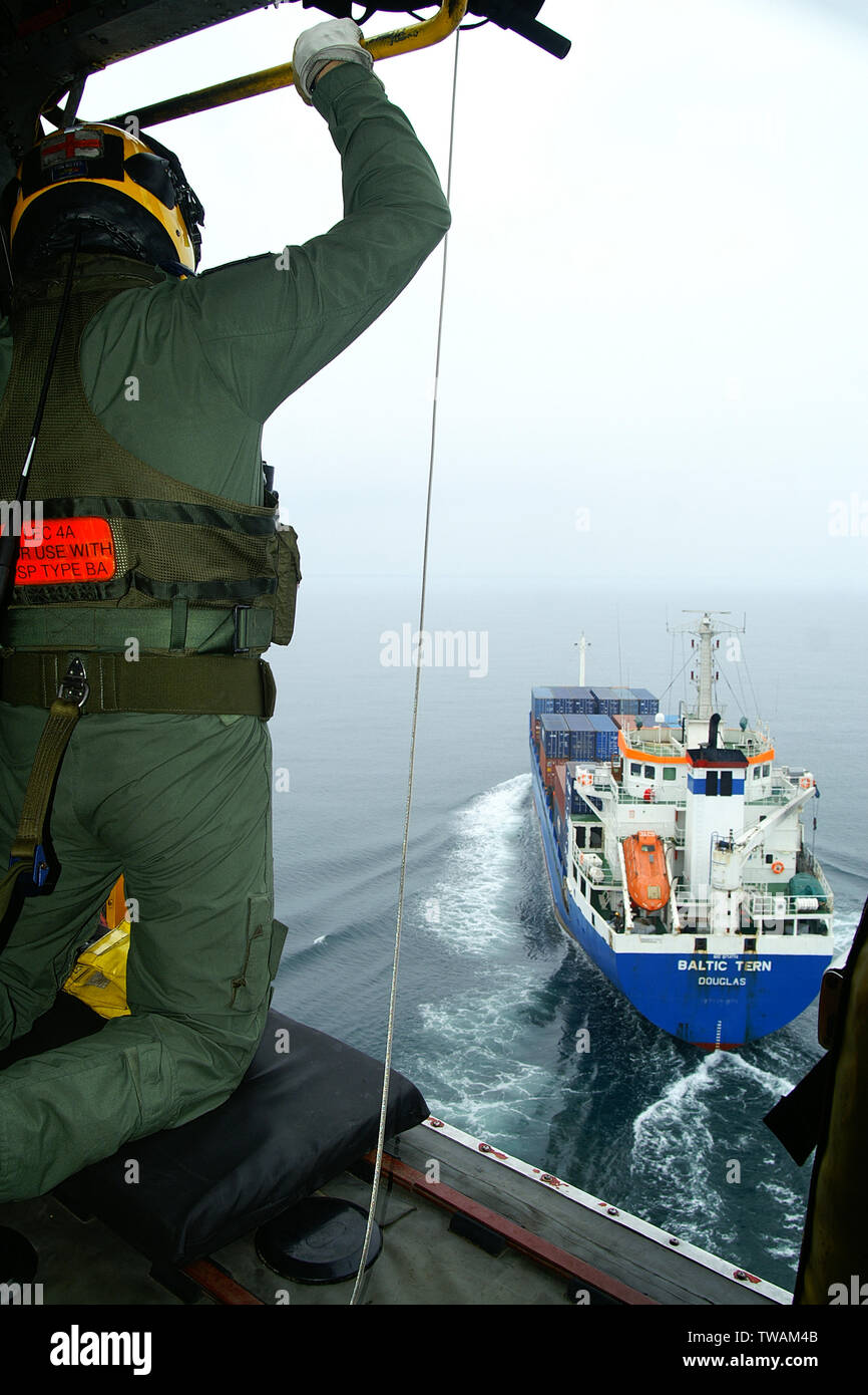 Rescue helicopter approaching container ship Stock Photo