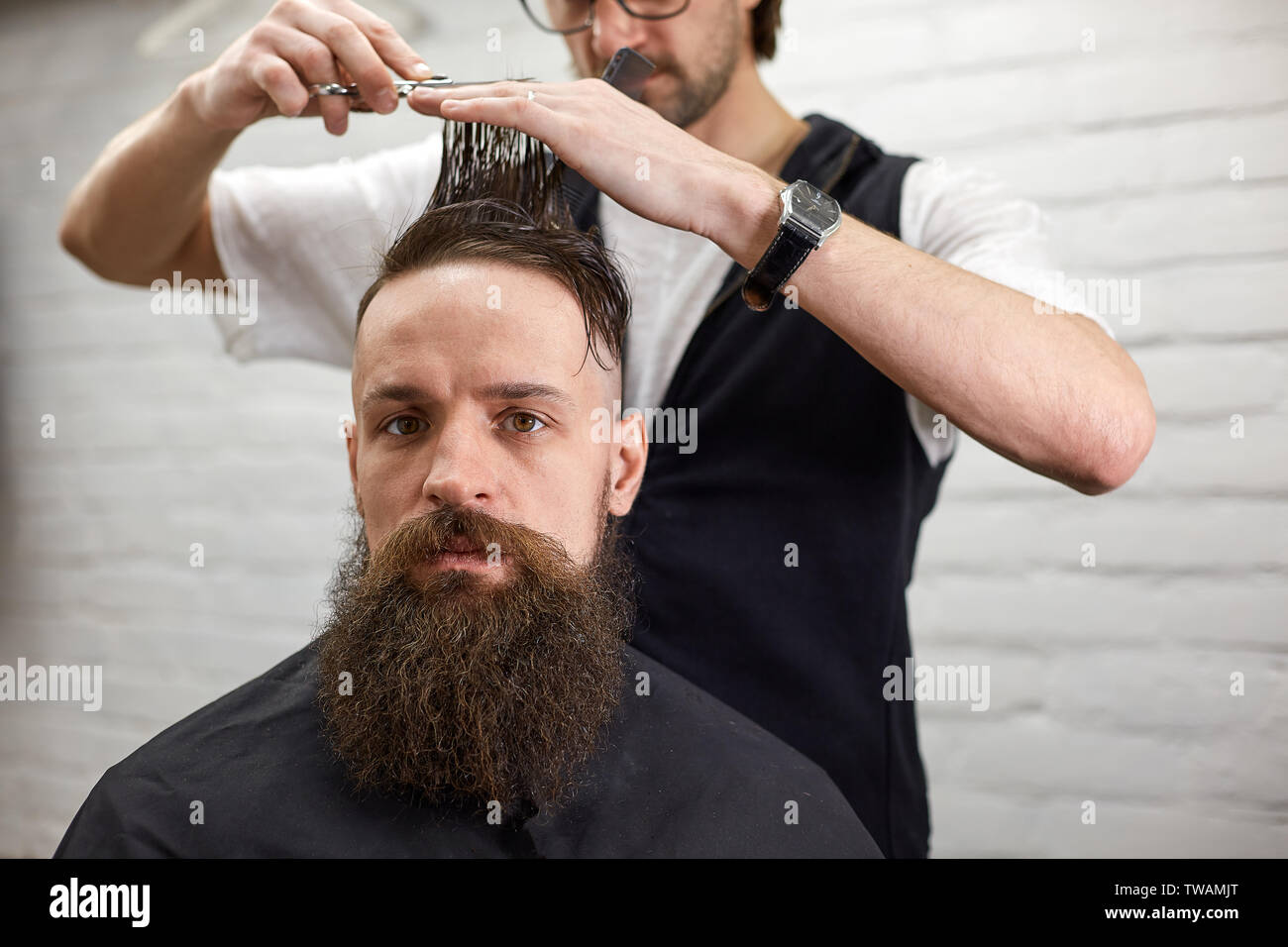Master cuts hair and beard of men in the barbershop, hairdresser makes  hairstyle for a young man Stock Photo - Alamy