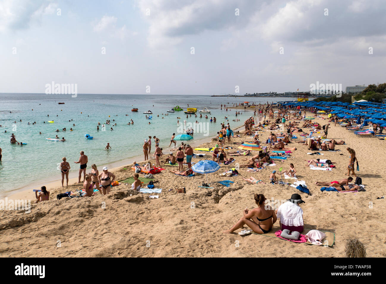 Beach with tourists relaxing on the beach, swimming and playing games